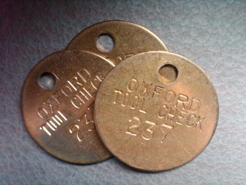 vintage brass stamped tags. tool room check tags. 1.25 inch diameter.
